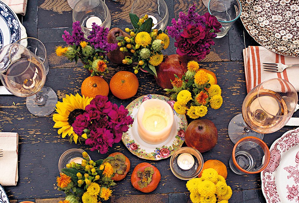 Il centrotavola autunnale con fiori, frutta e candele